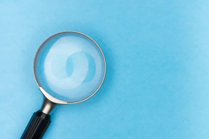 Magnifying glass hovering over a blue tile background
