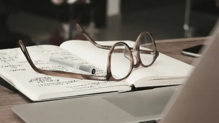 Pair of glasses and pen resting on a stack of papers